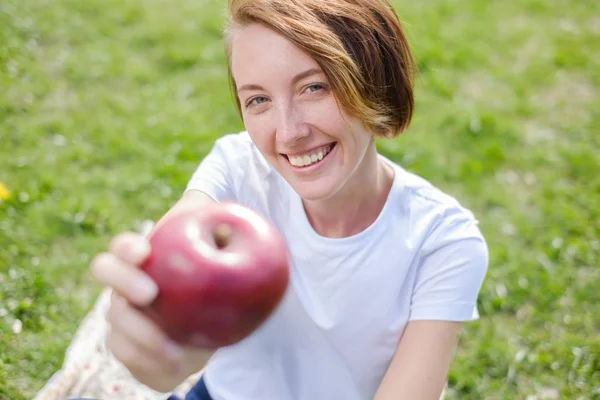 公園で赤いリンゴを食べて非常に美しい白人モデル. — ストック写真