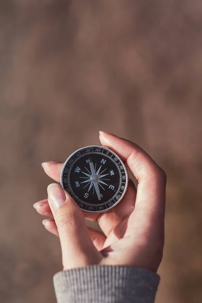 Hand holding the black compass isolated on brown background. Find the right path. — Stock Photo, Image
