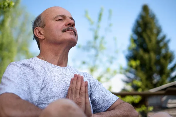 Joga w parku. Starszy mężczyzna z wąsem z namaste siedząc. Koncepcji spokoju i medytacji. — Zdjęcie stockowe