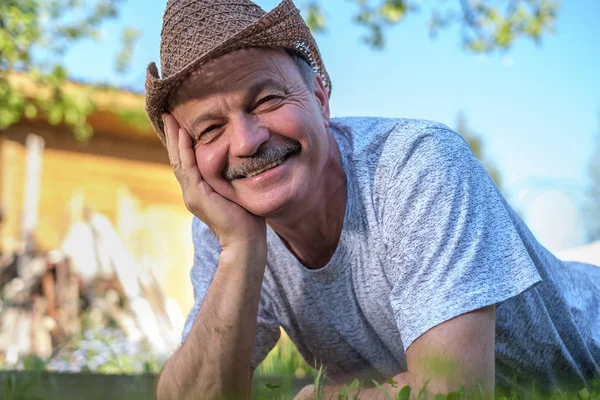 Портрет красивого літнього чоловіка Брехня на траві посміхається і дивиться на камеру . — стокове фото