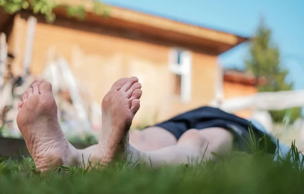 Un homme étendu sur un champ d'herbe. Il se relaxe sur la nature en été . — Photo