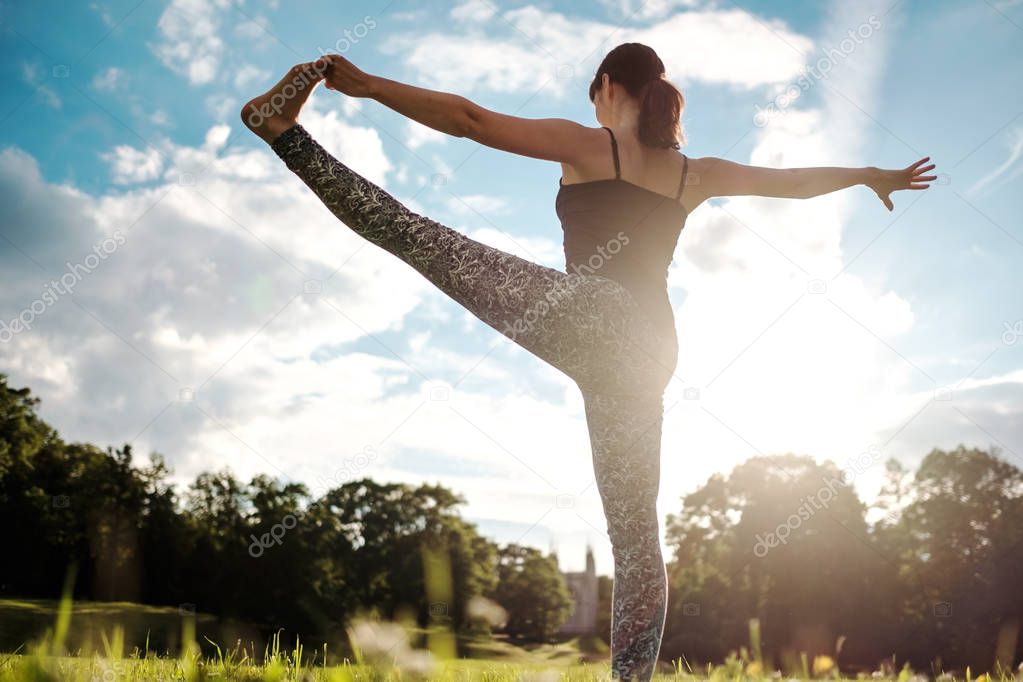 Caucasian woman in yoga standing balance Utthita Hasta Padangusthasana pose. Back view