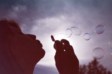 Düşük açılı kabarcıklar güneşli mavi gökyüzü karşı esen bir kadın silüeti görünümünü kapat.