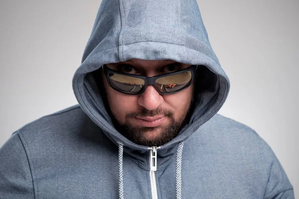 A mysterious bearded man in sunglasses hid under a hood. — Stock Photo, Image