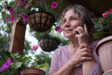 Telefonla arama ve çiçeklere bakarak Olgun kadın
