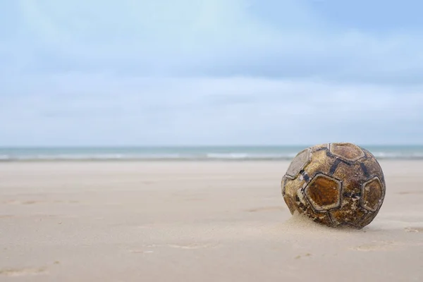 Pelota de fútbol de cuero viejo se sienta en la playa de arena —  Fotos de Stock