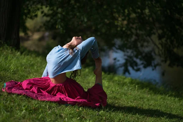 Hermosa joven en falda roja practicando Yoga asana en la naturaleza — Foto de Stock