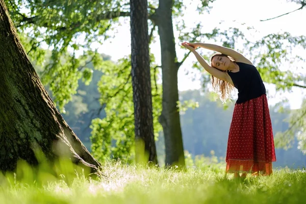 Atractiva joven hembra en falda roja está practicando yoga y haciendo asana por la mañana . — Foto de Stock