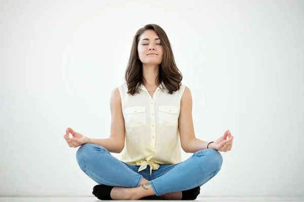 Portrait of a casual pretty woman meditating on the floor on white background — Stock Photo, Image