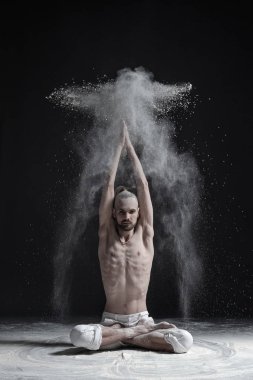 Bir yoga öğretmeni bir sukhasana siyah bir zemin üzerine oturuyor.