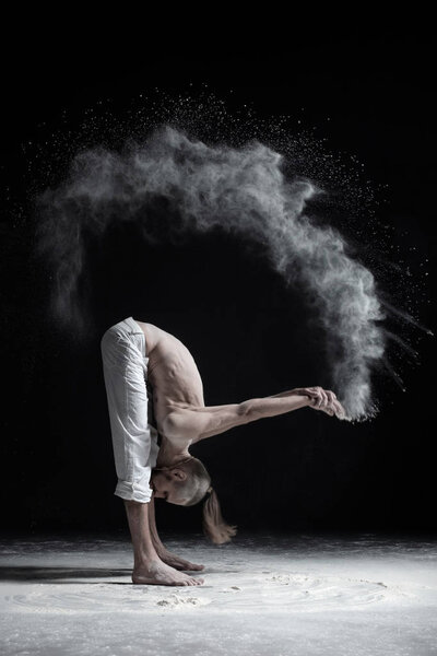 Flexible yoga man in standing forward fold uttanasana