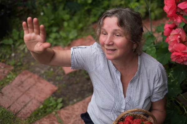 Vrolijke rijpe vrouw zit in de tuin en wuivende aan vrienden — Stockfoto