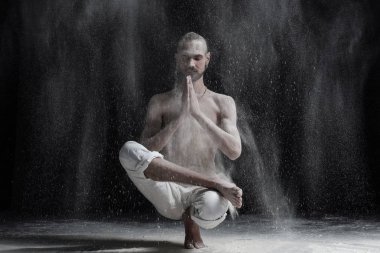 Yoga yapan beyaz erkek genç sakin veya pilates egzersiz. Bodur bulunduğu, yarım Lotus ayak dengesi oturan