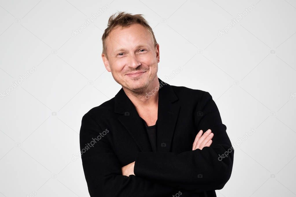 Smiling young man in black clothesstanding against white background