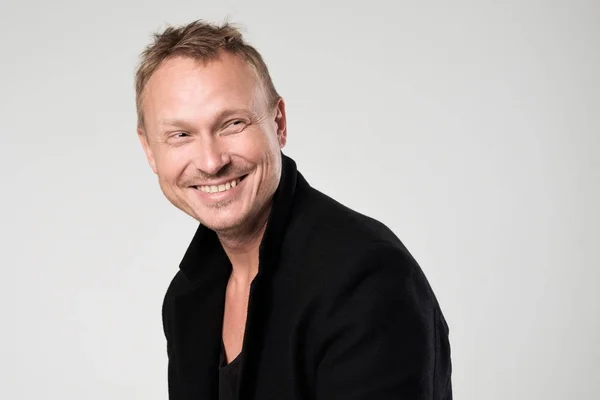 Smiling young man in black clothesstanding against white background — Stock Photo, Image