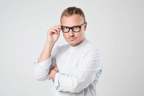 Portrait of a smart serious young man in shirt standing against — Stock Photo, Image