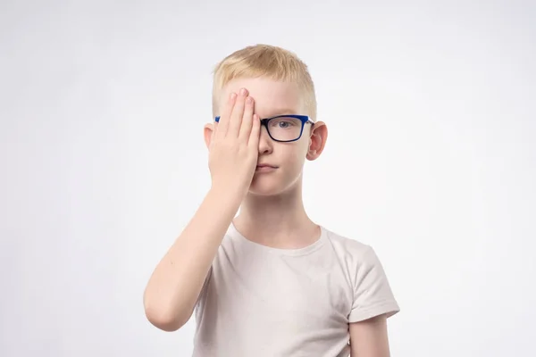 Criança loira branca revisando a visão fechando metade do rosto com a mão . — Fotografia de Stock