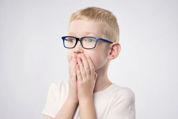 Scared litle kid boy with blond hair holding hands on face because he is afraid — Stock Photo, Image