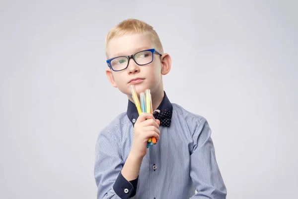 Caucasian boy with blond hair holding pencils in hands and looking up — Stock Photo, Image