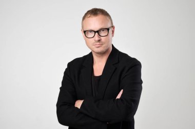 Gülümseyen genç adam ayakta beyaz arka plan üzerinde siyah giysili