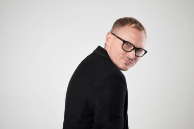 Gülümseyen genç adam ayakta beyaz arka plan üzerinde siyah giysili