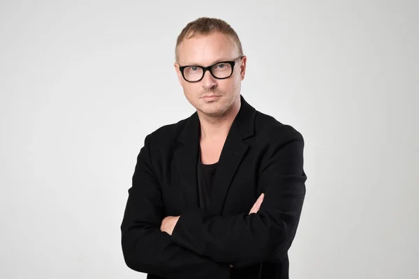 Gülümseyen genç adam ayakta beyaz arka plan üzerinde siyah giysili