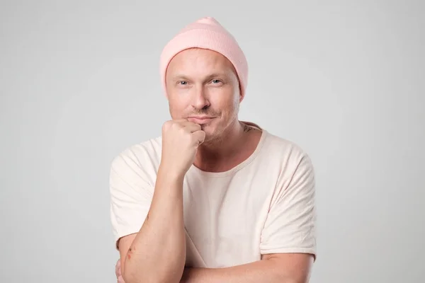 Uśmiechający się młody człowiek w różowe ubrania i stojący kapelusz na białym tle. — Zdjęcie stockowe