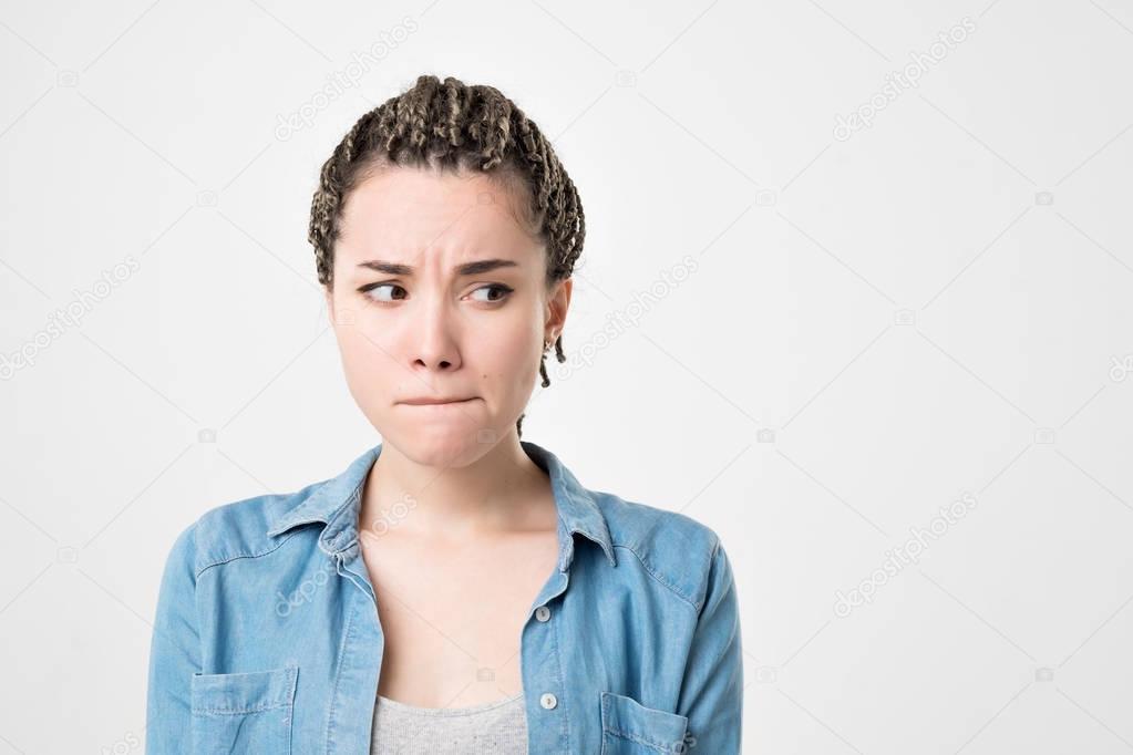 Pensive doubtful caucasian girl with braids looking sideways, feeling unsure. She making an important decision
