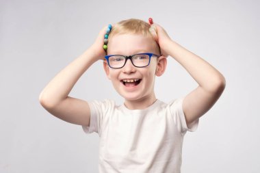 İşaretleyicileri elinde tutan mutlu küçük çocuk gülüyor.