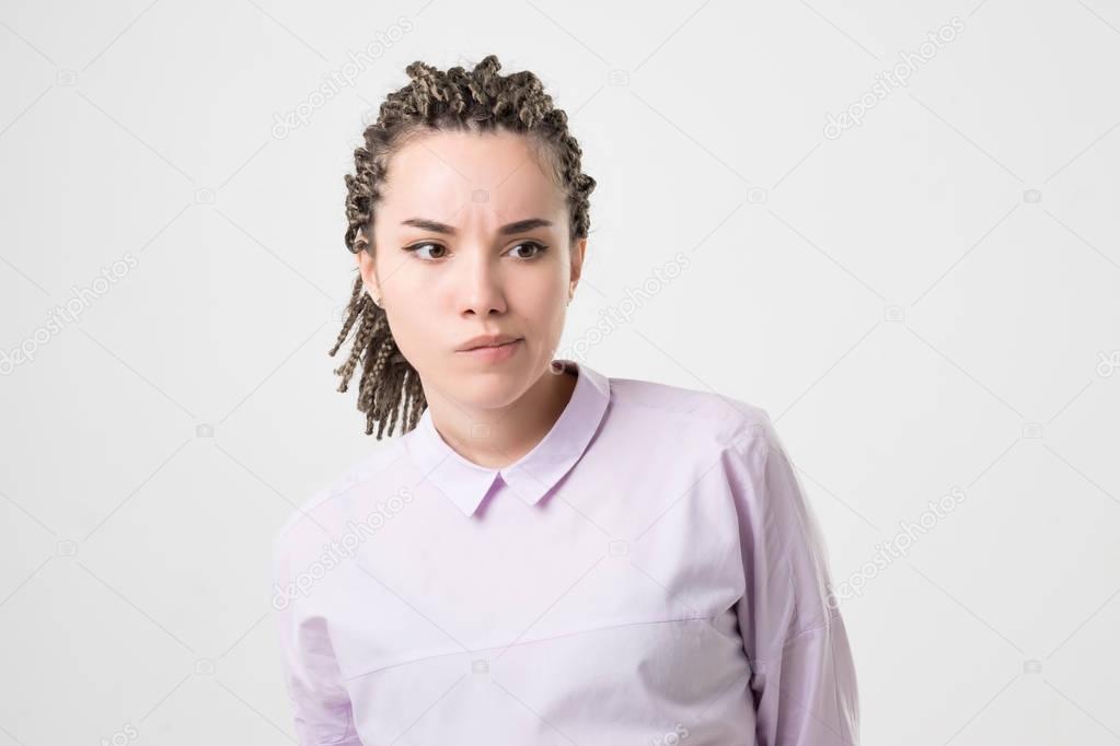 Pensive doubtful caucasian girl with braids looking sideways, feeling unsure. She making an important decision