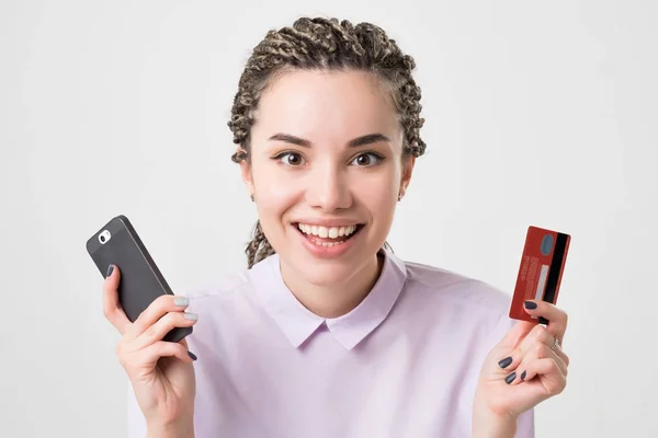 Feliz caucásico europeo joven mujer sosteniendo teléfono y tarjeta de hacer pedido en línea . — Foto de Stock