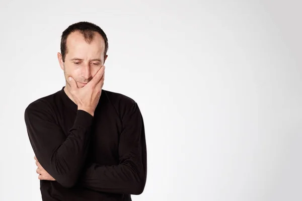 Kaukasischer Mann im schwarzen Hemd blickt mit skeptischer Rührung ins Gesicht — Stockfoto