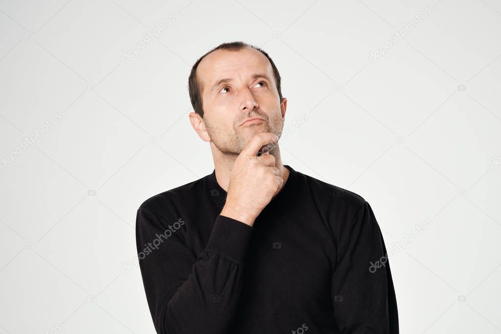 Caucasian man in black shirt looking down with skeptical emotion on face.
