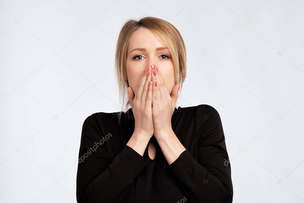 caucasian sad surprised excited woman in black dress covering with hands her mouth with blank copyspace.