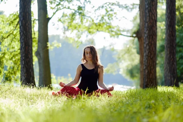 Mujer joven en falda roja disfrutando de meditación y yoga sobre hierba verde en el verano sobre la naturaleza —  Fotos de Stock