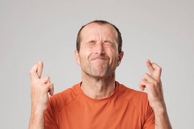 Mature hispanic man making a wish sign with crossing fingers isolated on background. clipart
