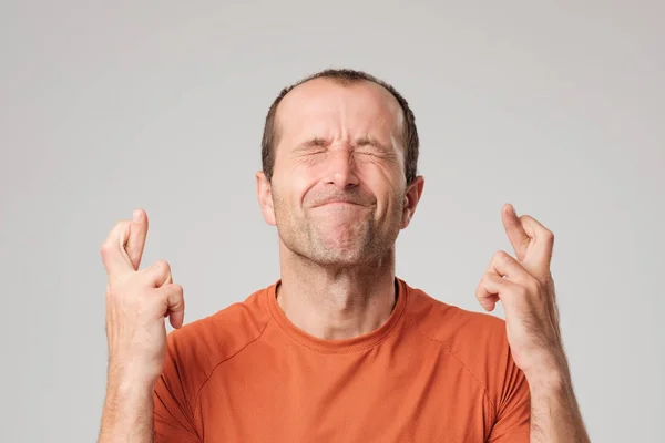 Volwassen Spaanse man die een wens ondertekenen met kruising vingers geïsoleerd op achtergrond. — Stockfoto