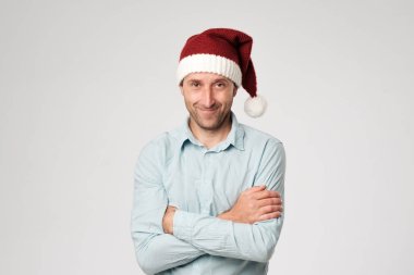 Santa claus şapka ayakta eller ile giyiyor rahat olgun adam beyaz arka plan üzerinde çarpı işareti.