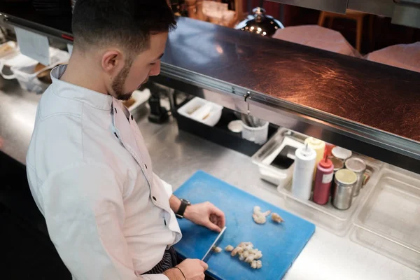 Шеф-кухар ріже сирі креветки з великим спеціальним ножем — стокове фото