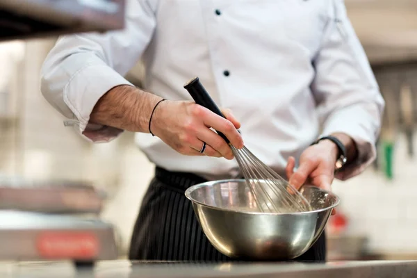 Chef in hotel or restaurant kitchen cooking, only hands. He is whisking ingredients. — Stock Photo, Image