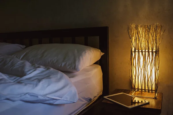 Um quarto acolhedor com uma cama e um tablet. Trabalhar em casa em condições confortáveis . — Fotografia de Stock
