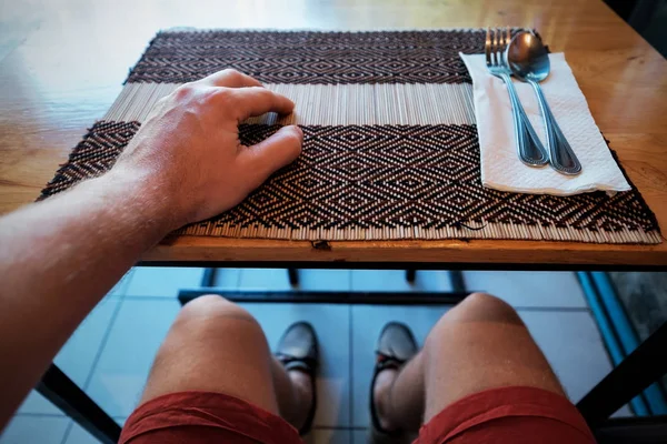 Człowiek czeka na obiad w kawiarni. Ludowe i łyżka leżą w pobliżu. — Zdjęcie stockowe