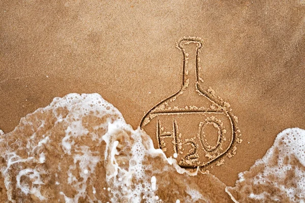 Målade kolv och kemiska formeln för vatten på sand. Vattenkvaliteten på stranden och havet. — Stockfoto