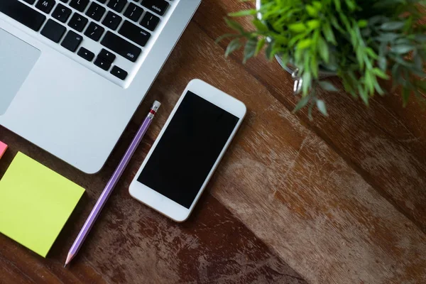 Ovanifrån av skrivbord bord med laptop, telefon, blomma och gul klistermärken — Stockfoto