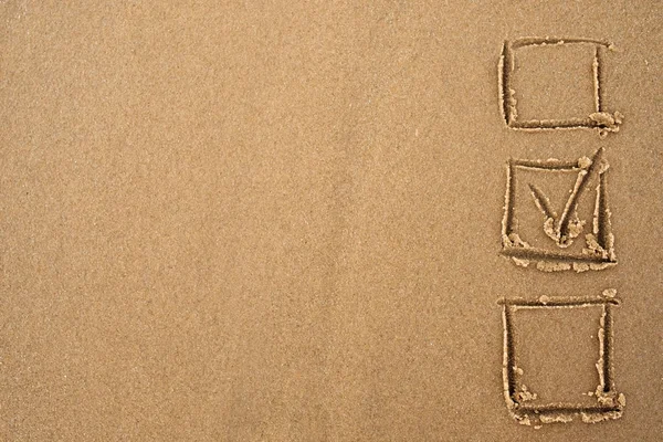 Das Konzept der Wahl. ein Häkchen im Fragebogen auf dem Sand. — Stockfoto
