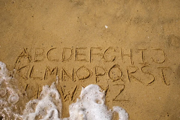 Alfabeto come testo sulla sabbia sulla spiaggia — Foto Stock