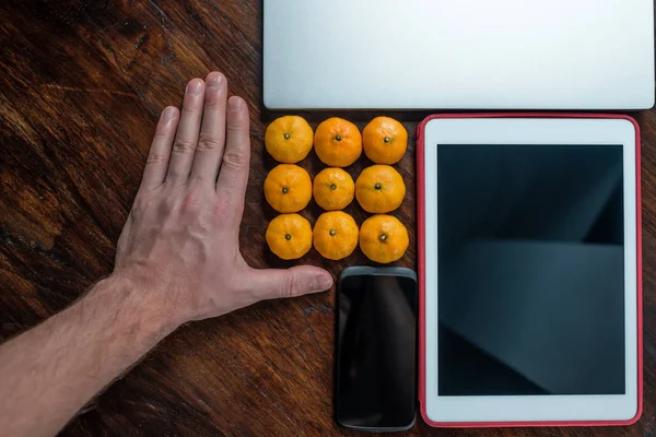 Человек положил мандарины рядом с ноутбуком и планшетом — стоковое фото
