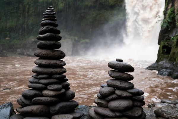 Wysokie wieże z płaskich kamieni cairn określonymi na bank przy wodospadzie. Tradycje buddyzmu. — Zdjęcie stockowe
