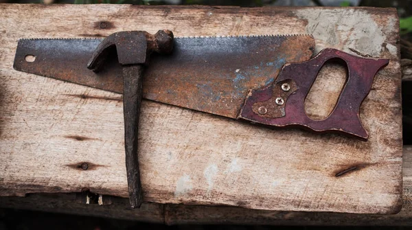 Старые ржавые инструменты молоток и ручная пила для работы — стоковое фото