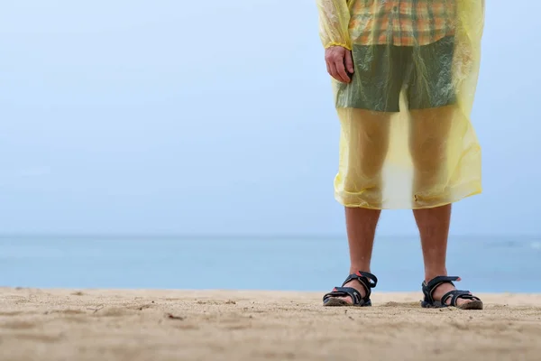 Человек на берегу океана или моря в дождевом плаще — стоковое фото